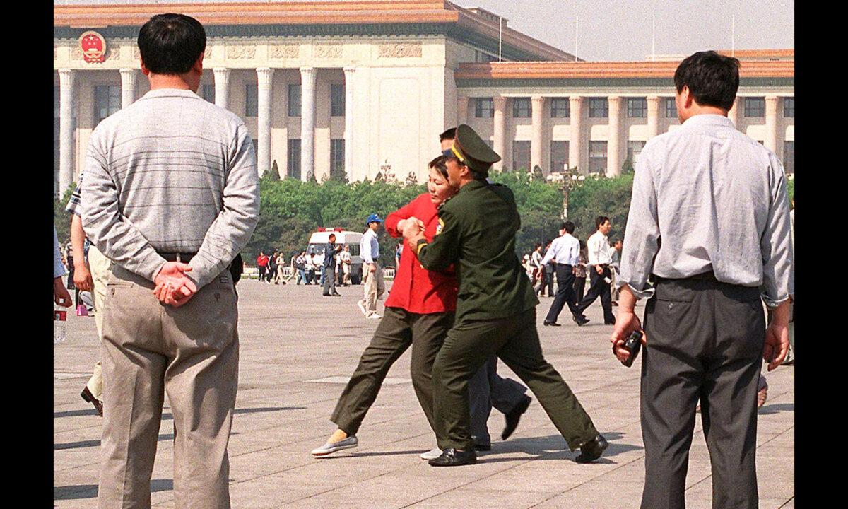 Plainclothes policemen watch as a female practitioner of the Falun Gong spiritual system is being forcefully taken away by Chinese police toward a police van in Tiananmen Square, Beijing, China, on May 11, 2000. (Stephen Shaver/AFP via Getty Images)
