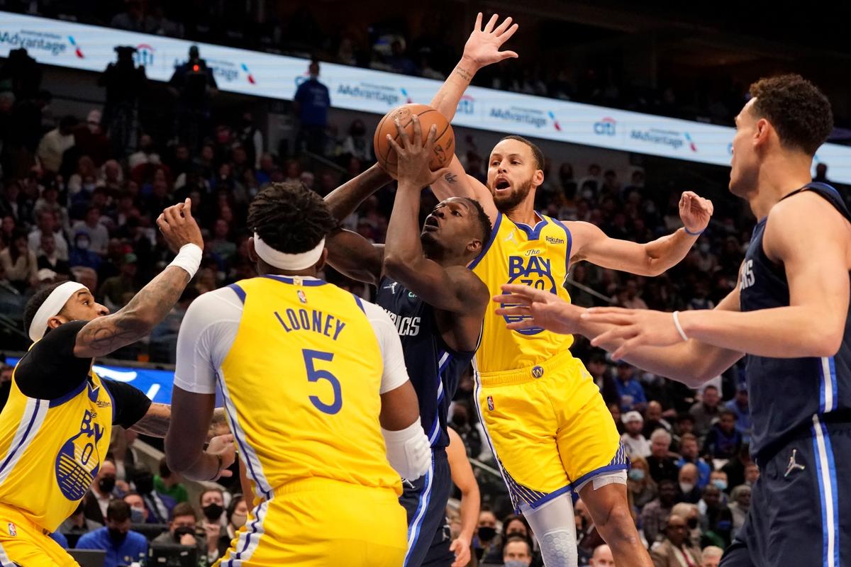 Dallas Mavericks forward Dorian Finney-Smith (10) tries to get past Golden State Warriors defenders Stephen Curry (30), Gary Payton II (0) and Kevon Looney (5) during the first quarter of an NBA basketball game in Dallas, on Jan. 5, 2022. (LM Otero/AP Photo)