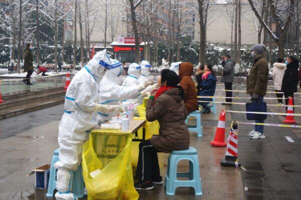 Medical workers in protective suits collect swabs from residents during a citywide nucleic acid testing following cases of COVID-19 in Zhengzhou, Henan Province, China, on Jan. 5, 2022. (cnsphoto via Reuters)