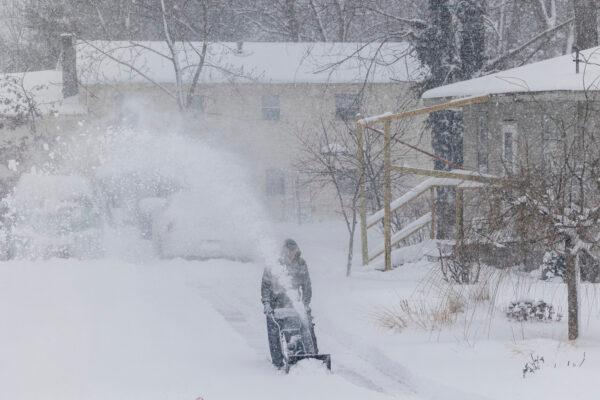 A person uses a snowblower to remove snow from a driveway after a winter storm in Walker, Mich., on Jan. 6, 2022. (Joel Bissell/MLive.com/Kalamazoo Gazette via AP)