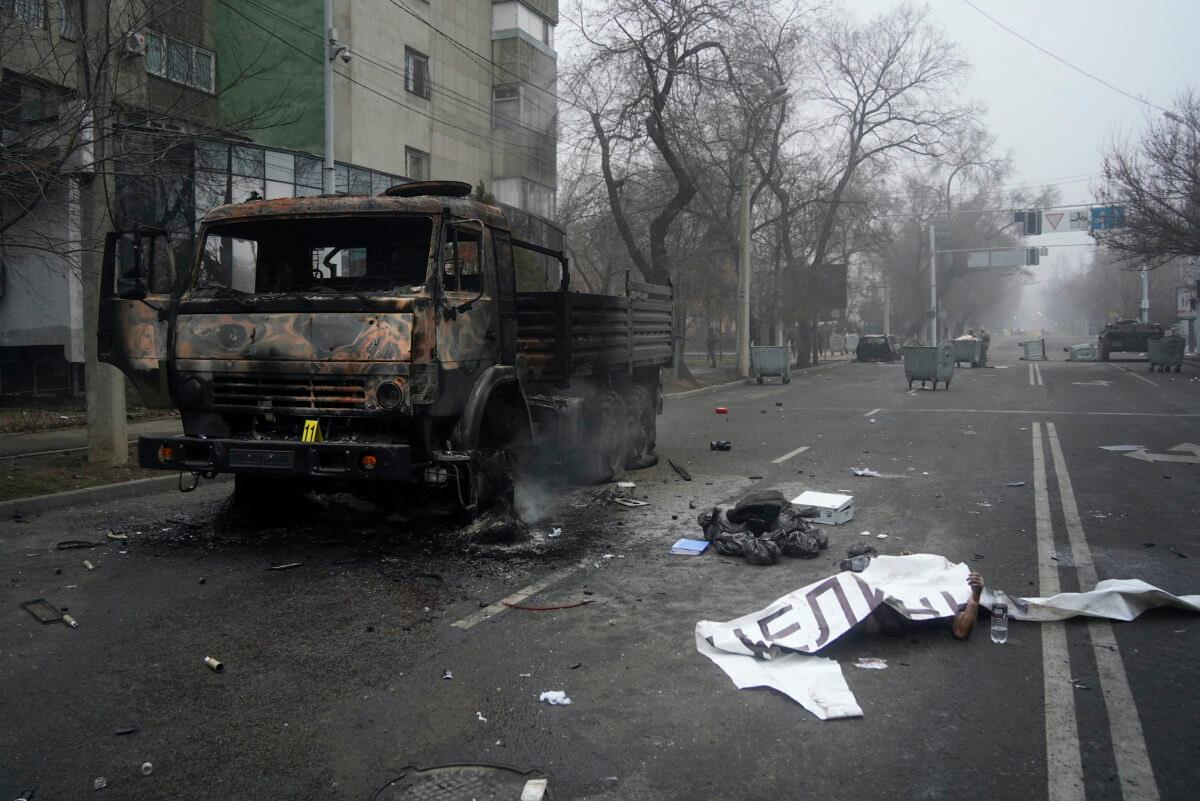 A victim's body covered by a banner (R), lays near to a military truck, which was burned after clashes, in Almaty, Kazakhstan, on Jan. 6, 2022. (Vladimir Tretyakov/NUR.KZ via AP)