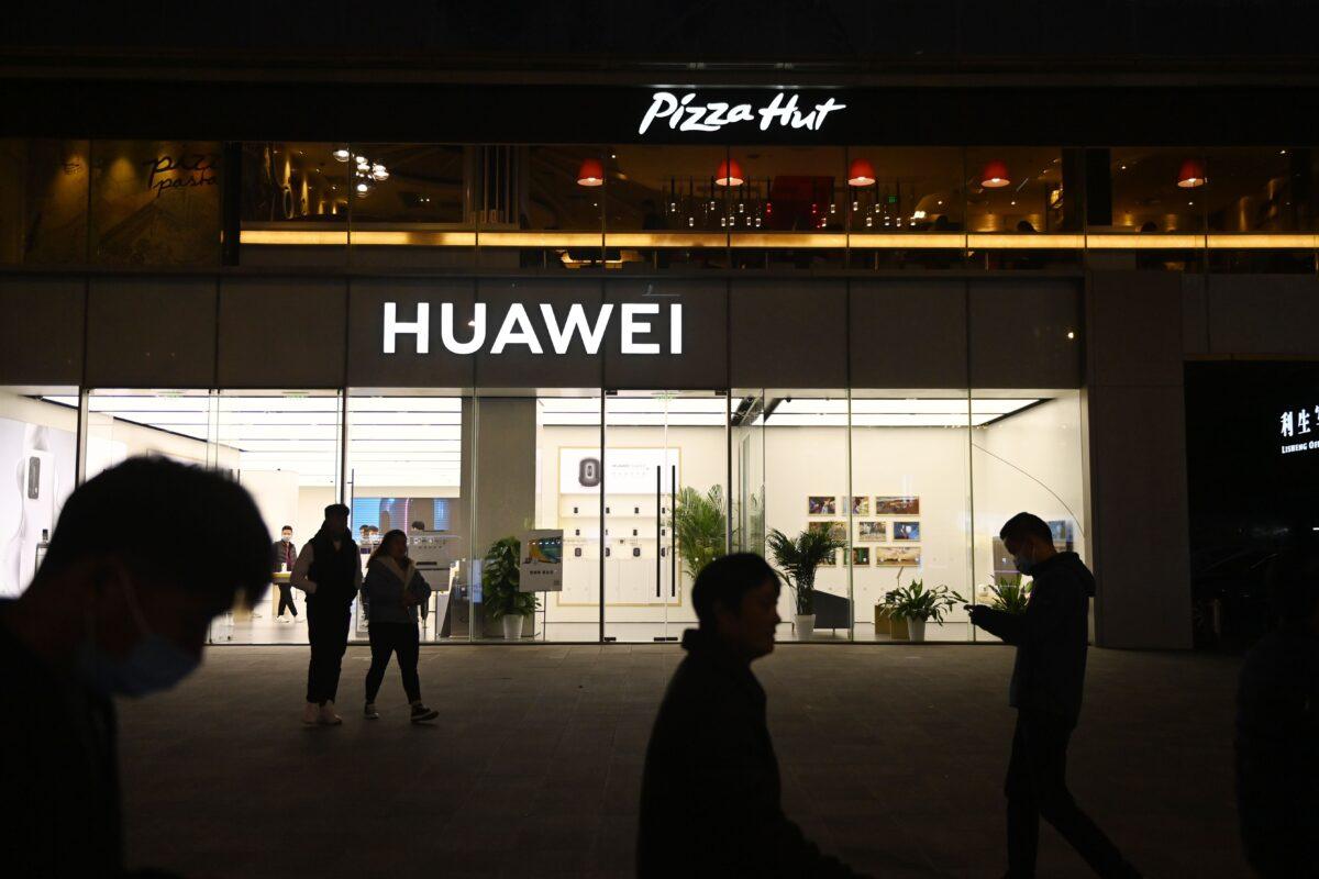 People walk past a Huawei store below a Pizza Hut in Beijing on Oct. 22, 2020. (Greg Baker/AFP via Getty Images)