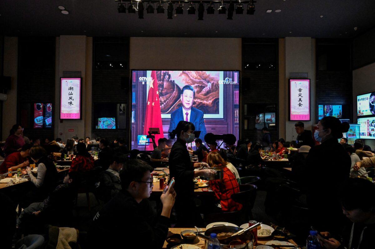 People have their dinner at a restaurant as a screen broadcasts Chinese leader Xi Jinping delivering his New Year speech in Beijing on Dec. 31, 2021. (Jade Gao/AFP via Getty Images)