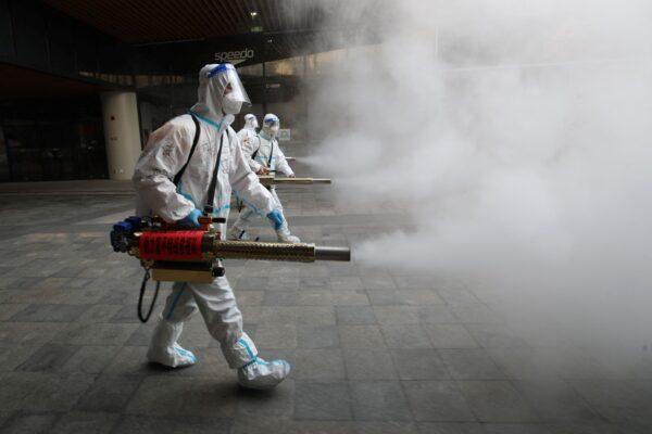 Staff members wearing personal protective equipment spray disinfectant outside a shopping mall in Xi'an, China, on Jan. 11, 2022. (STR/AFP via Getty Images)