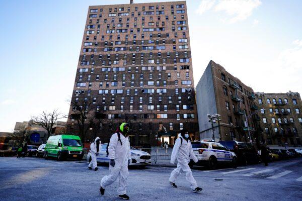 Workers in protective clothing walk from an apartment building in the Bronx borough of New York City, on Jan. 11, 2022. (Matt Rourke/AP Photo)