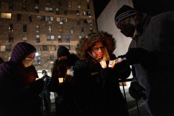 People prepare candles during a candlelight vigil outside the apartment building in the Bronx borough of New York, on Jan. 11, 2022. (Yuki Iwamura/AP Photo)