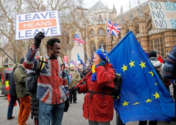 A pro-Brexit activist (L) holding a placard and wearing a union flag-themed shirt talks with an anti-Brexit demonstrator holding an EU flag as they protest near the Houses of Parliament in London, England, on Jan. 29, 2019. (Tolga Akmen/AFP via Getty Images)