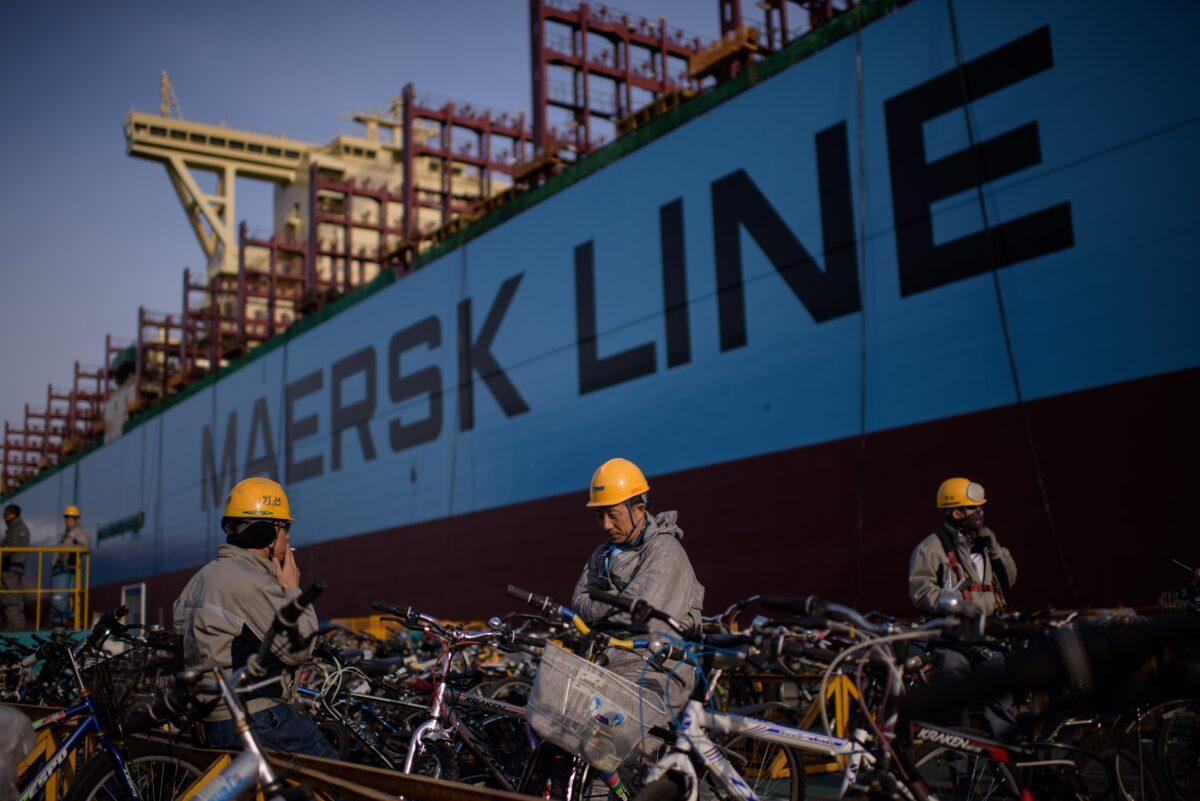 Workers take a break outside an under-construction Maersk triple-E class container ship at the Daewoo DSME shipyard in Okpo, South Korea, on Dec. 3, 2014. (Ed Jones/AFP via Getty Images)