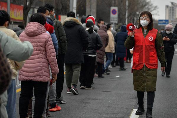 A woman uses a loudspeaker to give advice to residents as they line up during a mass testing in Tianjin, China, on Jan. 9, 2022. (Sun Fanyue/Xinhua via AP)