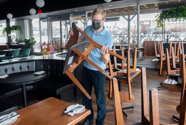 A staff member at a restaurant puts chairs on tables ahead of the 5 p.m. curfew in Montreal on Dec. 31, 2021. (The Canadian Press/Graham Hughes)