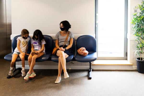A family sits during an observation period after the administration of their Pfizer COVID-19 vaccine at Sydney Road Family Medical Practice in Balgowlah, Sydney, Australia, on Jan. 11, 2022. (Photo by Jenny Evans/Getty Images)