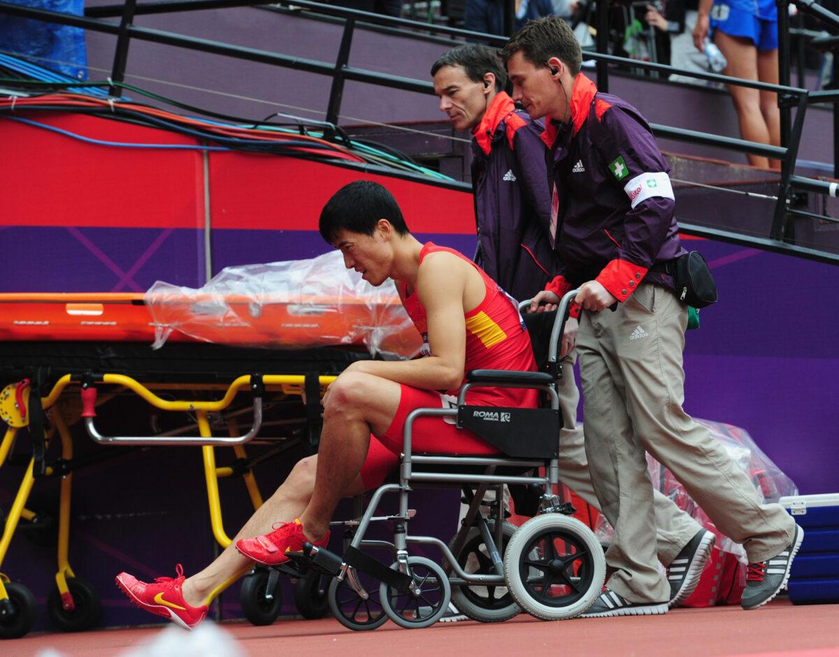 Liu Xiang of China gets assisted off the track after getting injured in the Men's 110m Hurdles Round 1 Heats on Day 11 of the London 2012 Olympic Games at Olympic Stadium in London, England, on Aug. 7, 2012. (Stu Forster/Getty Images)