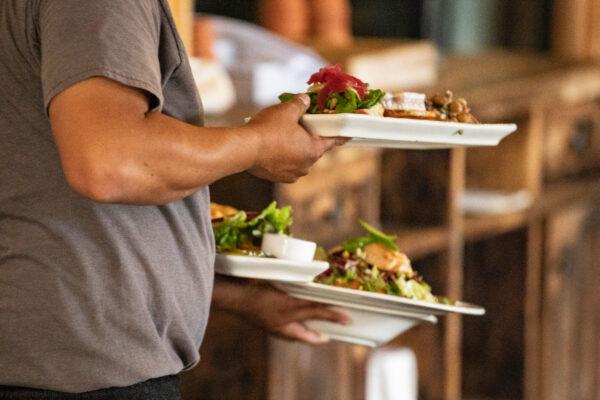 A waiter carries food at a restaurant in Newport Beach, Calif., on Sept. 9, 2020. (John Fredricks/The Epoch Times)