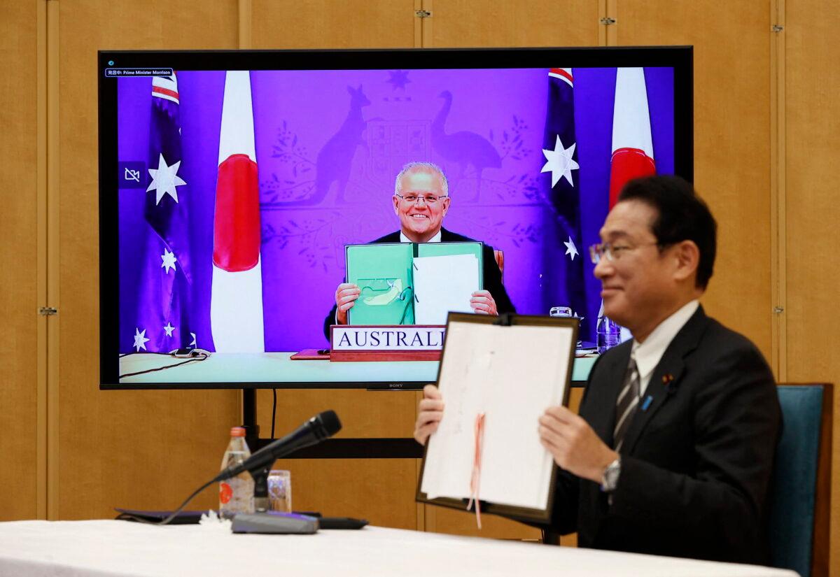 Japan's Prime Minister Fumio Kishida (R) and Australia's Prime Minister Scott Morrison hold signed documents during their video signing ceremony of the bilateral reciprocal access agreement at Kishida's official residence in Tokyo on Jan. 6, 2022. (Issei Kato/Pool/AFP via Getty Images)