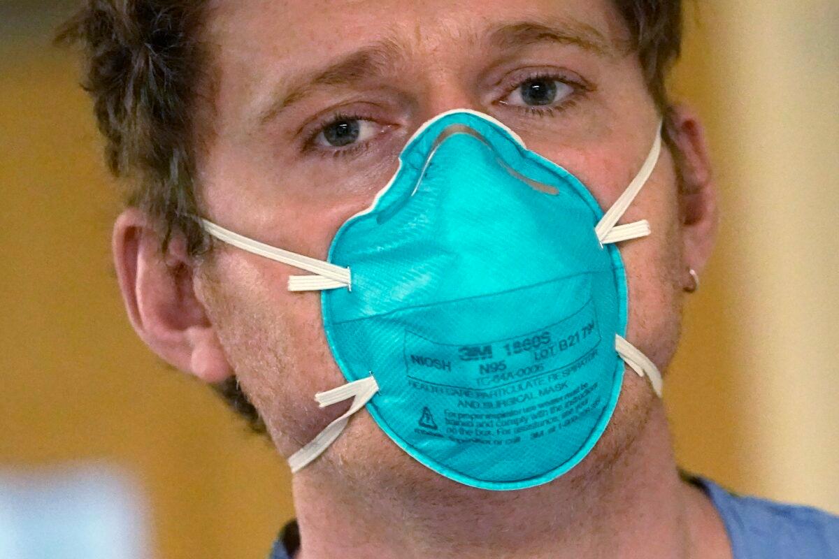 Registered nurse Scott McGieson wears an N95 mask as he walks out of a patient's room in the acute care unit of Harborview Medical Center in Seattle, on Jan. 14, 2022. (Elaine Thompson/AP Photo)