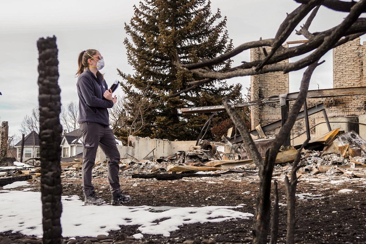 An insurance adjuster assesses damage to a house located in the Westminster Heights neighborhood of Louisville, Colo., where a fast-moving fire destroyed more than 1,000 homes and damaged a nearby shopping complex. (Allan Stein/The Epoch Times)