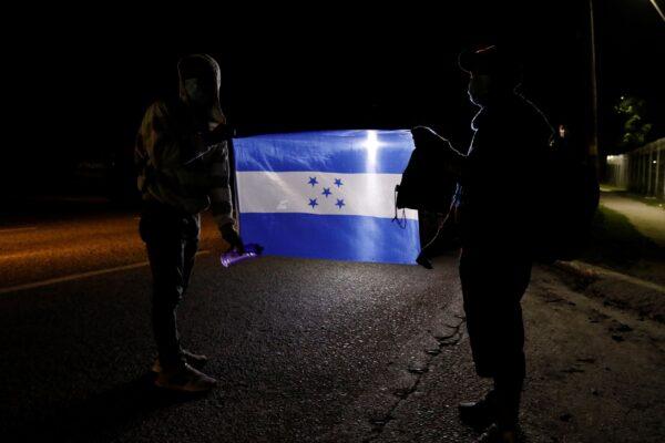 Members of a migrant caravan hold a Honduran national flag in San Pedro Sula, Honduras, on Jan. 15, 2022. (Delmer Martinez/AP Photo)