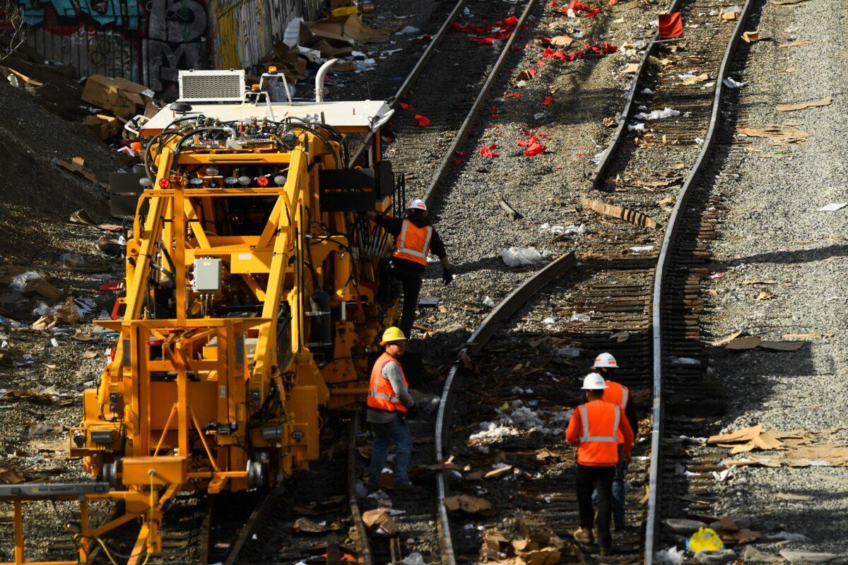 Railroad workers repair a section of Union Pacific train tracks after a train derailed from the tracks, which are littered with thousands of opened boxes and packages stolen from cargo shipping containers, in Los Angeles on Jan. 16, 2022. (Patrick T. Fallon/AFP via Getty Images)