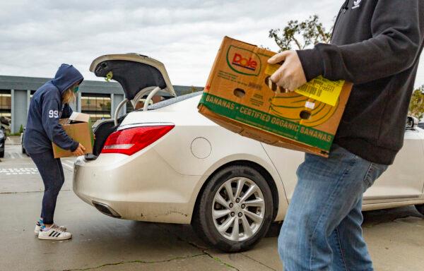 Volunteers at Laguna Niguel Presbyterian work with San Clemente based Family Assistance Minitries in handing out to food donations to a line of cars in Laguna Niguel, Calif., on Dec. 23, 2021. (John Fredricks/The Epoch Times)