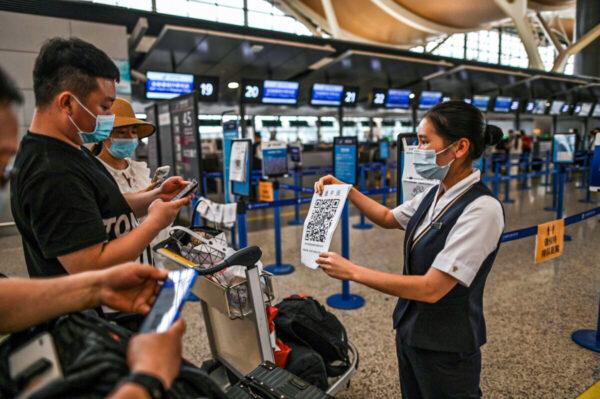  Passengers wearing face masks check their health code with a sheet held by an airport staff (R) at Pudong International Airport in Shanghai, China, on June 11, 2020. (Hector Retamal/AFP via Getty Images)