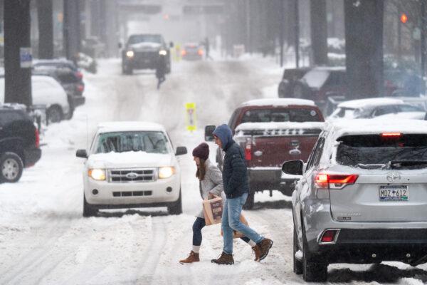 Pedestrians cross a street as motorists drive through the snow on Jan.16, 2022, in Greenville, S.C. (Sean Rayford/Getty Images)