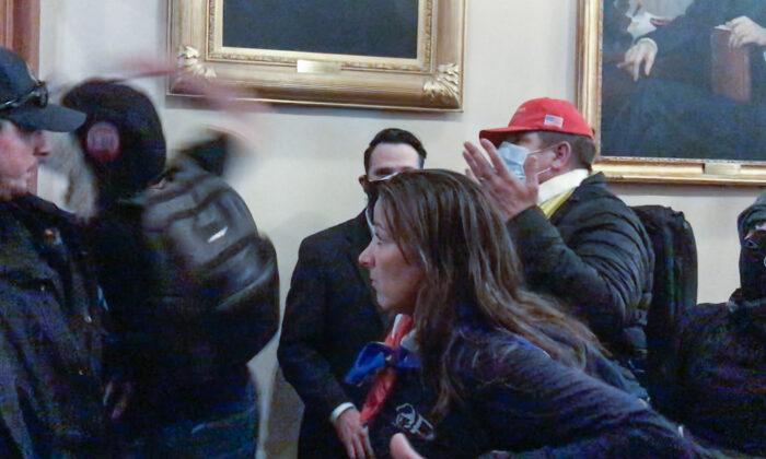 Ashli Babbitt watches as rioter Zachary Alam punches the glass in the door of the Speaker's Lobby at the U.S. Capitol on Jan. 6, 2021. (Video Still / ©Tayler Hansen)