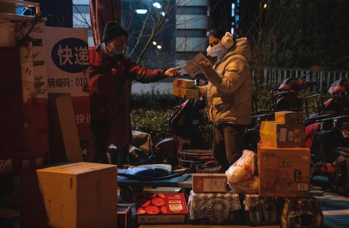A woman looks at a parcel near a delivery man in Beijing on Jan. 18, 2022. (AP Photo/Ng Han Guan)