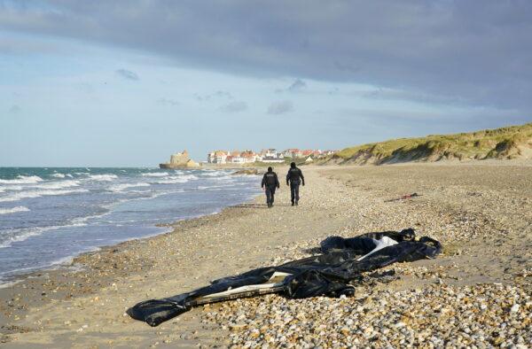 French police pass a deflated dinghy on the beach in Wimereux near Calais, France, on Nov. 18, 2021. (Gareth Fuller/PA)