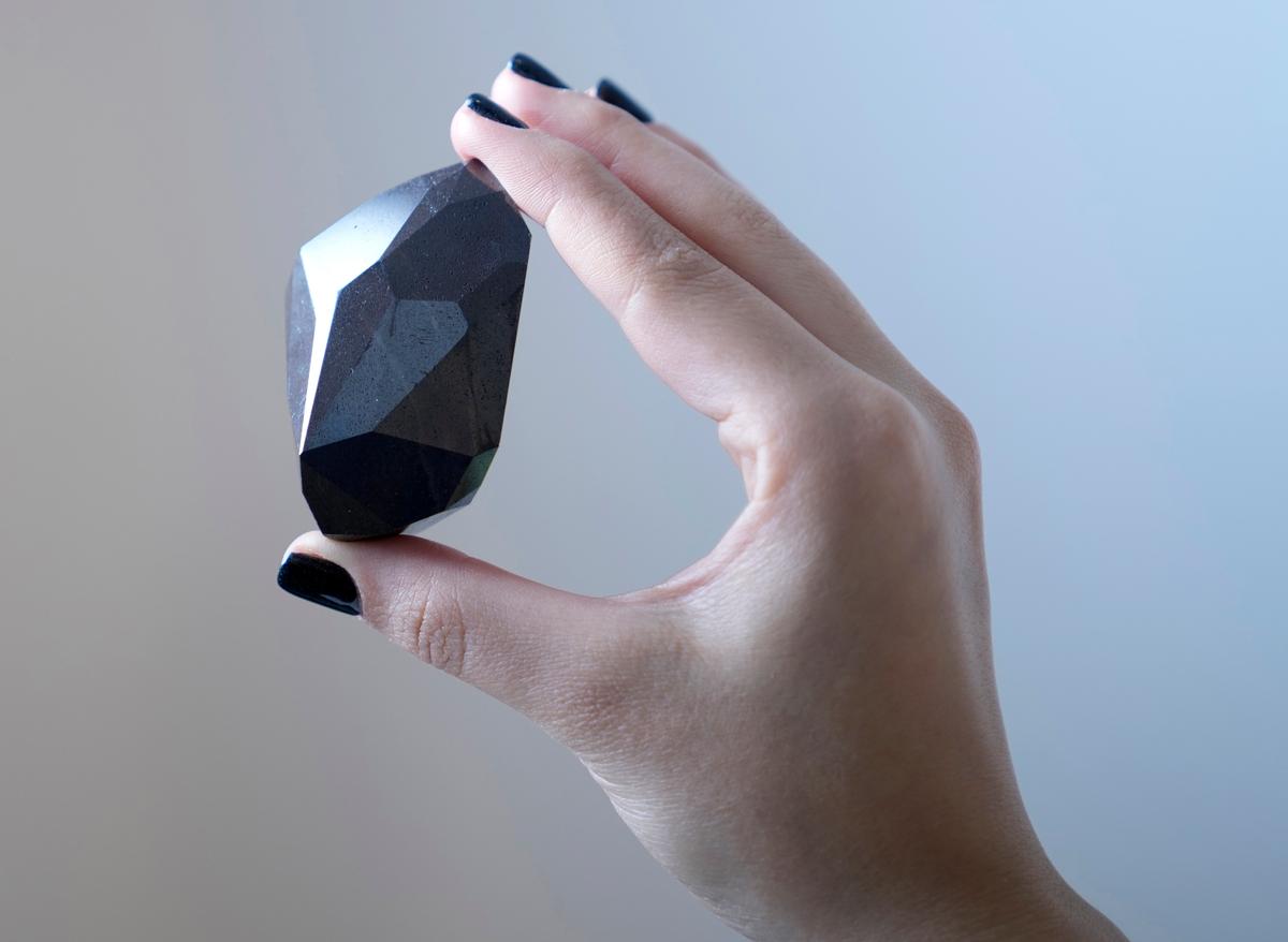 An employee of Sotheby's Dubai presents a 555.55-carat black diamond, "The Enigma," to be auctioned at Sotheby's Dubai gallery, in Dubai, United Arab Emirates, Monday, Jan. 17, 2022. (Kamran Jebreili/AP Photo)