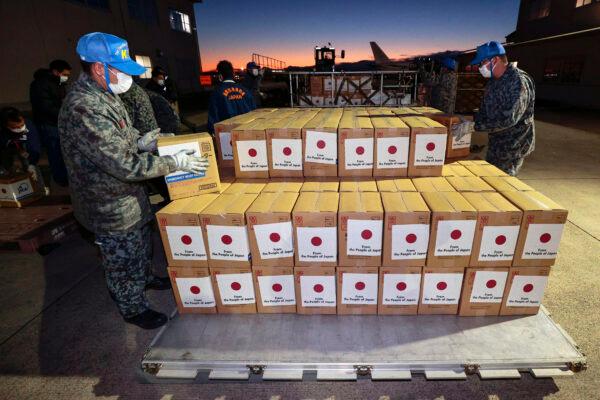  Members of Japan's Air Self-Defense Force help load boxes of emergency relief goods into an airplane at an airbase in Komaki, central Japan, on Jan. 20, 2022. (Kyodo News via AP)