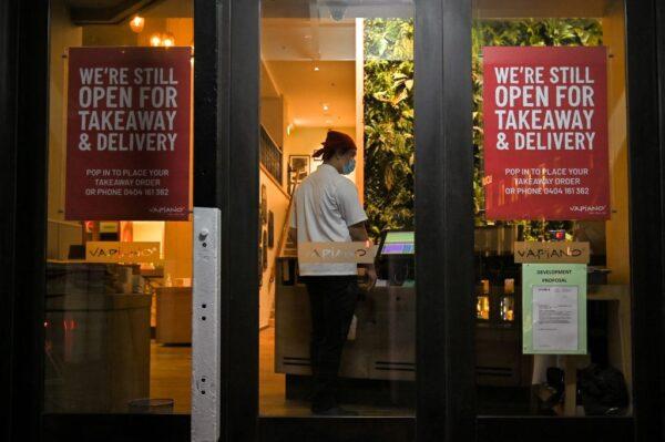 A restaurant worker stands at the entrance of an eatery open for takeaway food along a quiet street in central Sydney, Australia, on June 27, 2021. (Steven Saphore/AFP via Getty Images)
