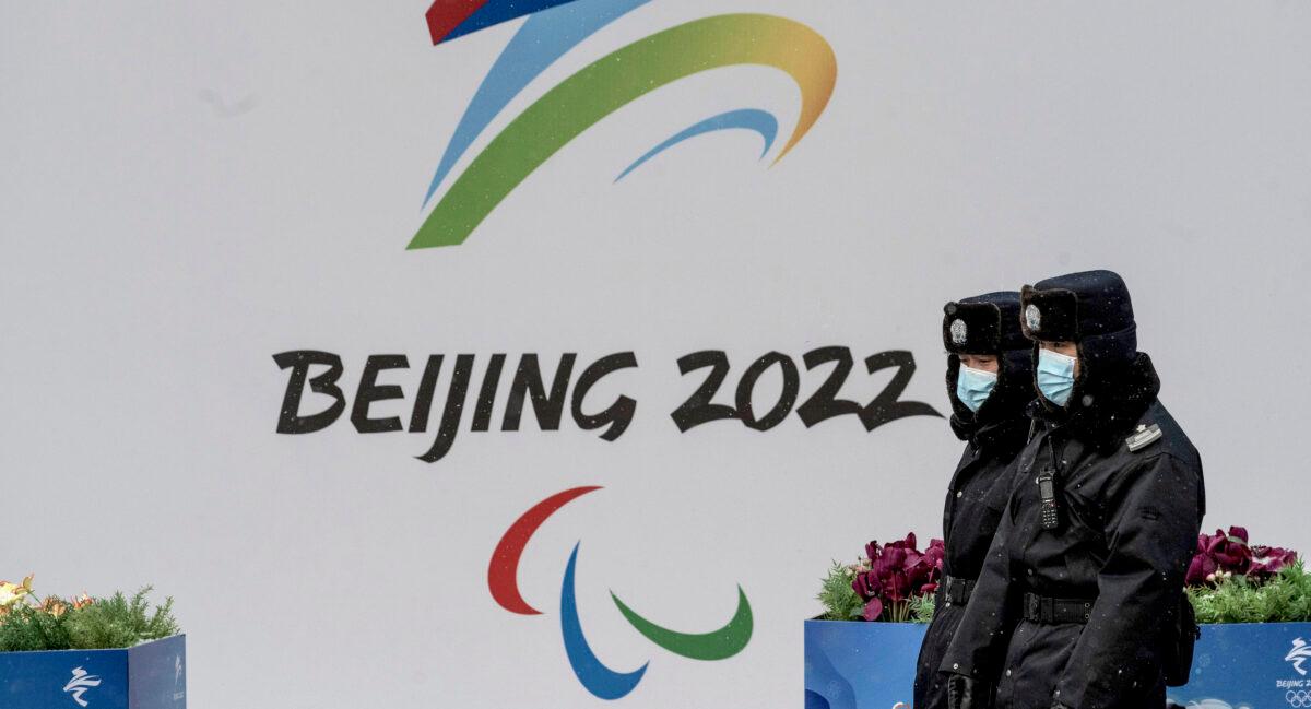 Chinese security guards pass a billboard for the 2022 Winter Olympics in Beijing, on Jan. 20, 2022. (Kevin Frayer/Getty Images)