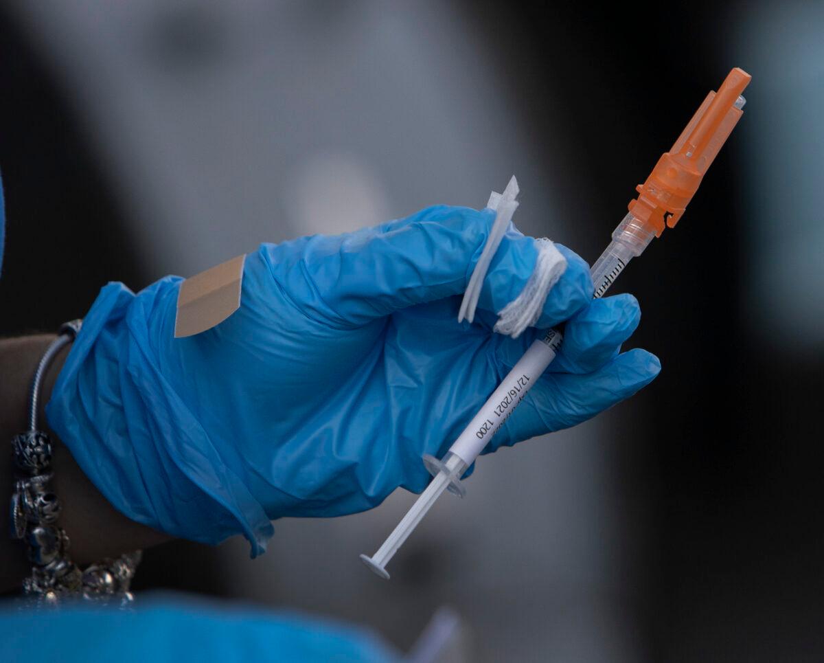 A health care worker holds a Pfizer-BioNTech COVID-19 vaccine in Miami, Fla., on Dec. 16, 2021. (Joe Raedle/Getty Images)