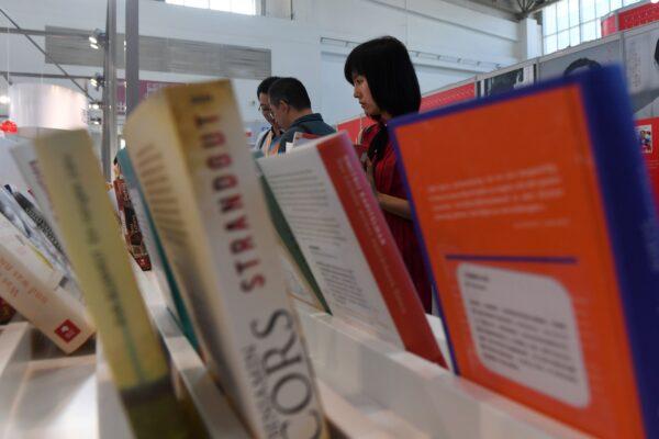 People look at books at the Beijing International Book Fair in Beijing. Just days after an outcry over an attempt to censor a UK academic journal in China, hundreds of international publishing houses court importers at a major book fair in Beijing on Aug. 23, 2017. (GREG BAKER/AFP via Getty Images)