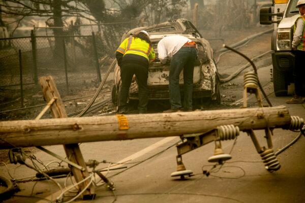 Eric England, right, searches through a friend's vehicle after the wildfire burned through Paradise in Calif., on Nov. 10, 2018. (AP Photo/Noah Berger)