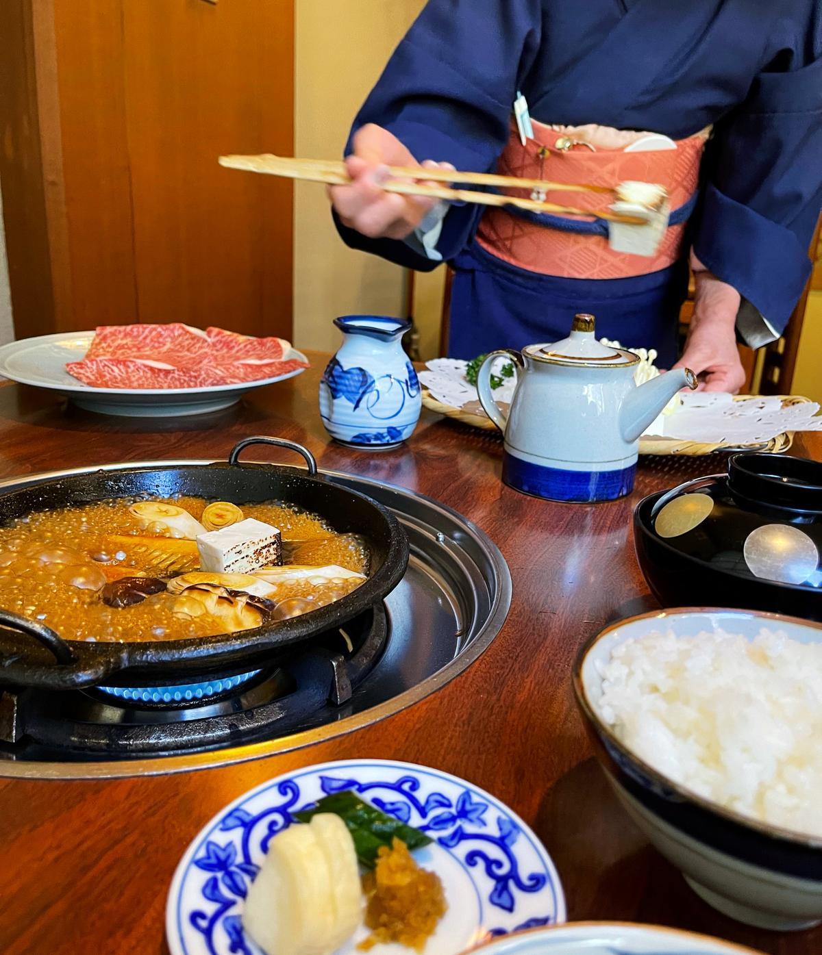 The skilled nakai, professional servers, place the ingredients in the simmering sauce to cook. (Melissa Uchiyama)