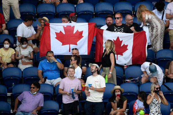 Supporters of Canada's Denis Shapovalov hold up their national flag during his quarterfinal against Rafael Nadal of Spain at the Australian Open tennis championships in Melbourne, Australia, on Jan. 25, 2022. (Andy Brownbill/AP Photo)