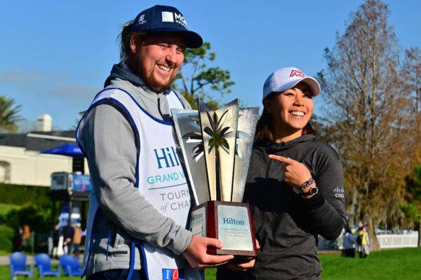 Danielle Kang of the United States and caddie Olly Brett pose with the trophy after winning the 2022 Hilton Grand Vacations Tournament of Champions at Lake Nona Golf & Country Club, in Orlando, on Jan. 23, 2022. (Julio Aguilar/Getty Images)