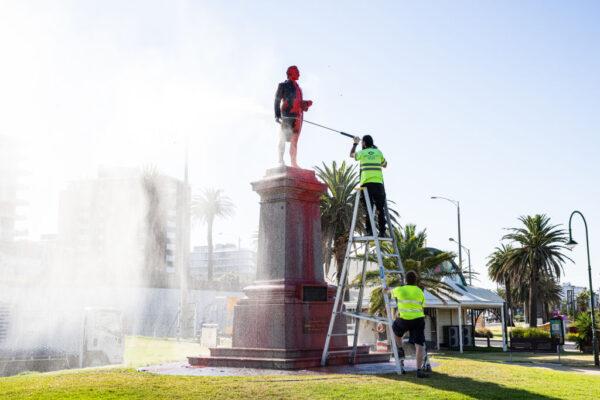 Workers wash off red paint that was poured on the statue of Captain Cook at St. Kilda beach in Melbourne, Australia, on Jan. 26, 2022. (Diego Fedele/Getty Images)