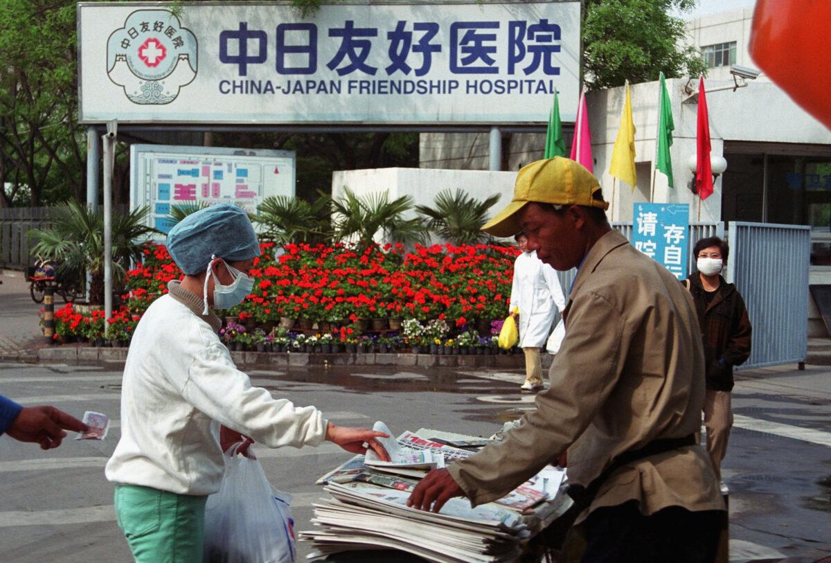 A nurse buys a newspaper from a street vendor in front of the China-Japan Friendship Hospital in Beijing, China, on April 29, 2003. (Getty Images)