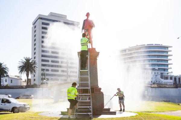 Workers wash off red paint that was poured on a statue of Captain Cook at St. Kilda beach in Melbourne, Australia, on Jan. 26, 2022. (Diego Fedele/Getty Images)