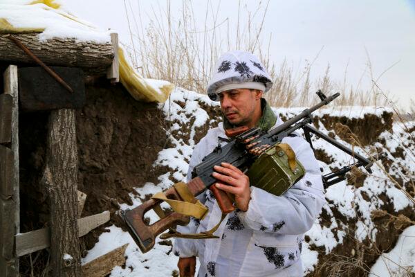 A serviceman carries his machine gun into a shelter in the territory controlled by pro-Russian militants at the front line with Ukrainian government forces in Slavyanoserbsk, Luhansk region, eastern Ukraine, on Jan. 25, 2022. (Alexei Alexandrov/AP Photo)