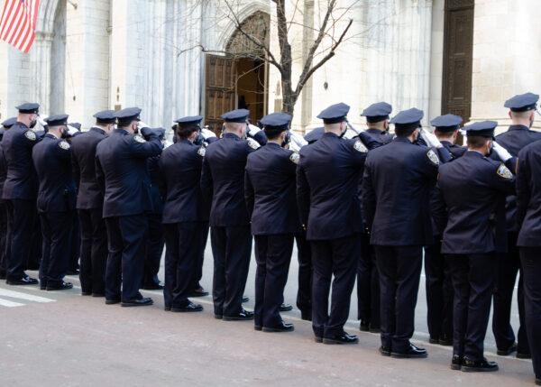 NYPD officers salute as the casket of Jason Rivera is carried into St. Patrick’s Cathedral in NYC for his wake on Jan. 27, 2022. (Dave Paone/The Epoch Times)