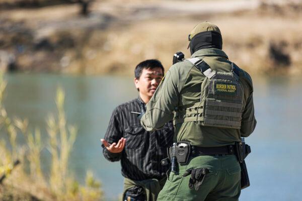 A Border Patrol agent talks to a Chinese man who just waded across the Rio Grande from Mexico into Eagle Pass, Texas, on Jan. 25, 2022. (Charlotte Cuthbertson/The Epoch Times)