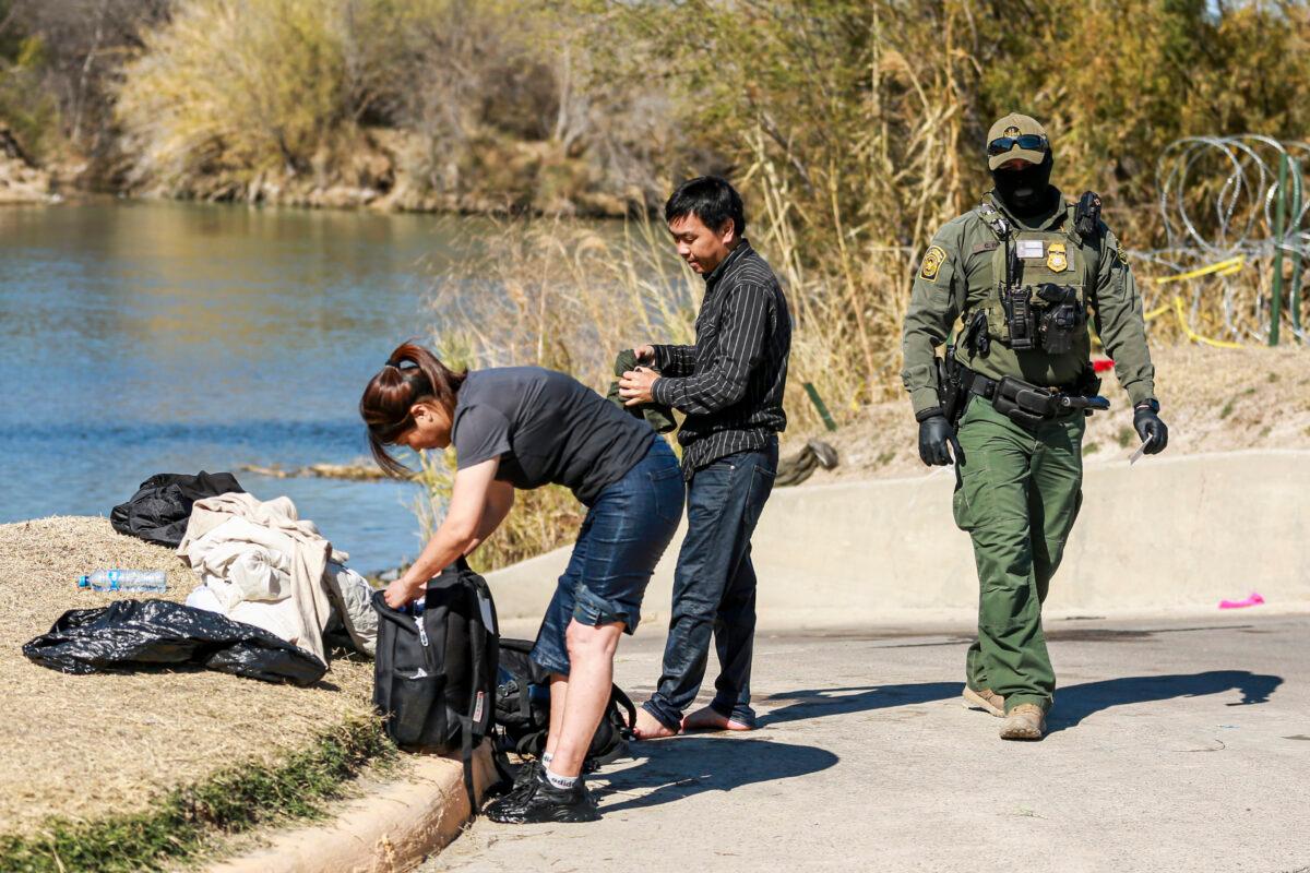A Border Patrol agent apprehends a Chinese couple that just waded across the Rio Grande from Mexico into Eagle Pass, Texas, on Jan. 25, 2022. (Charlotte Cuthbertson/The Epoch Times)