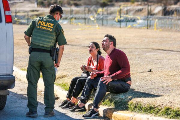 A Border Patrol agent apprehends a Cuban couple that just waded across the Rio Grande from Mexico into Eagle Pass, Texas, on Jan. 25, 2022. (Charlotte Cuthbertson/The Epoch Times)