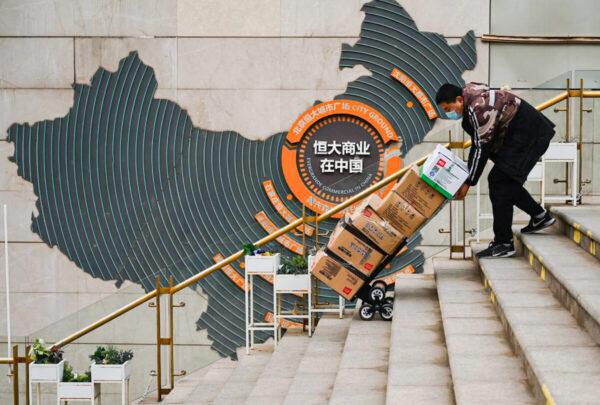 A worker in front of a sign showing Evergrande Group's China operation at one of the company's housing complexes in Beijing on Dec. 8, 2021. (Noel Celis/AFP via Getty Images)