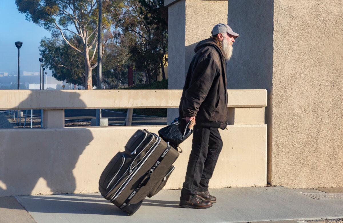 A homeless man walks with his items in Irvine, Calif., on Jan. 27, 2022. (John Fredricks/The Epoch Times)