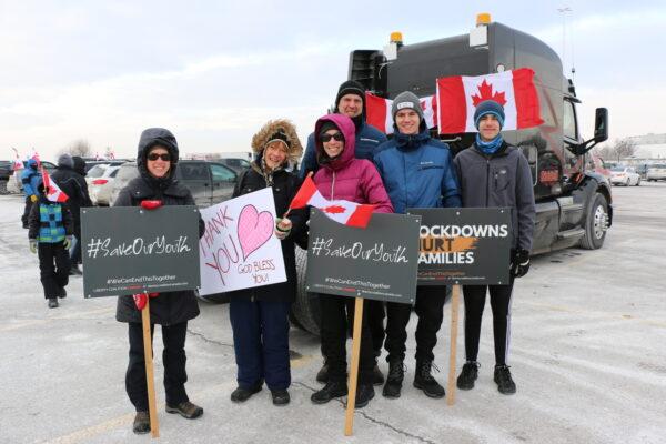 Convoy supporters Stacey Dittman (front C) with her husband (back C), two sons, Jenna Greatorex (2nd L), and another friend from Orangeville hold signs at Vaughan Mills on Jan. 27, 2022. (Andrew Chen/The Epoch Times)
