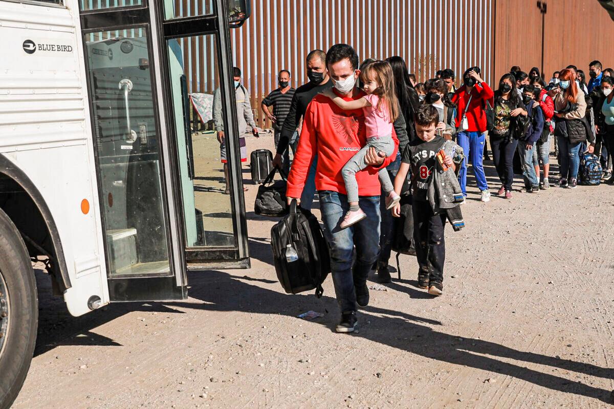 Illegal immigrants who have gathered by the border wall prepare to board a bus going to the Border Patrol station for processing in Yuma, Arizona, on Dec. 10, 2021. (Charlotte Cuthbertson/The Epoch Times)